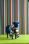 Blue sheep statue wearing scarf and sunglasses in front of striped wall