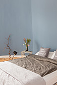 Doppelbett und Beistelltisch im Schlafzimmer mit blauer Wand