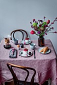 Frühstückstisch mit Kaffee, Kokosmilchjoghurt, Himbeeren, Ei, Dinkelcroissants und Blumenstrauss