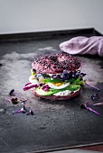 A beetroot bagel with spelt, black sesame, avocado, radicchio, egg, sakura curry, green peppers and fresh cheese