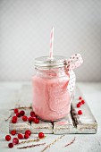 Gefrorener Trinkjoghurt mit roten Johannisbeeren im Schraubglas serviert