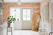 Wicker empress chair in bright hallway with brightly patterned wallpaper