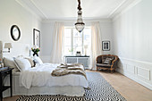 Elegantes Schlafzimmer mit Wandverkleidung und Stuckdecke
