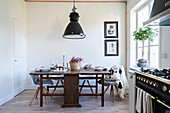 Old wooden table, modern chairs and gas cooker in kitchen