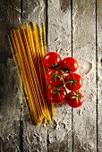 Cherry tomatoes with spaghetti and flour on a wooden table