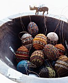 Easter eggs decorated with beads in rustic bowl with rhino figurine on rim