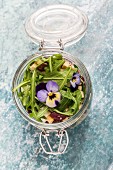 Quinoa salad with lambs lettuce, radicchio, rocket, croutons, goat's cheese and horned violets in a glass jar