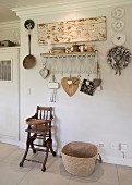 Vintage-style arrangement on wall with motto above vintage high chair and raffia shopping basket on tiled floor