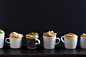 Various savoury mug cakes in front of a black background