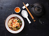 Asian Ramen noodles with broth in bowl serving size and Tea on dark background