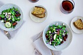 Bowls of Spicy Pecans Feta Arugula Salad served with bread and red wine