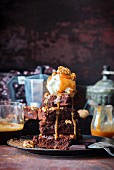 A stack of brownies with vanilla ice cream and caramel sauce