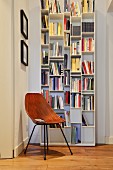 White bookcase and retro chair in reading corner in period apartment