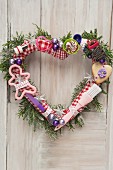 Heart-shaped Christmas door wreath decorated with baubles, baking utensils and biscuits