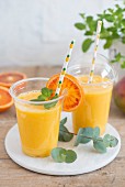 Smoothie mit Ananas-, Mango- und Orangesaft in Take Out Bechern