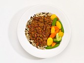 Low-fat chilli with vegetables and rice on a plate in front of a white background (seen from above)