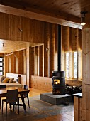 Black wood-burning stove on stone plinth in wooden house