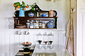 Antik Wandregal mit Porzellangefässen, Aufbewahrungsgläsern und Mandarinenzweig in der Küche
