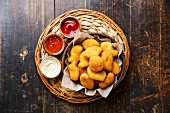 Chicken breast nuggets with three popular sauce for choice on wooden background