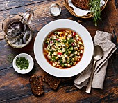 Cold Soup Okroshka with sausage, vegetables and kvass serving size on wooden table