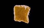 A candied ginger cube against a black background
