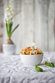 Colourful fusilli with pesto and parmesan in a white bowl on a table