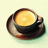Cup of aromatic coffee over vintage table close up