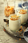 Homemade granola muesli with nuts and dried fruits and yogurt in glasses on rustic stone background