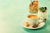 Gesundes Frühstück mit Kaffee, hausgemachtem Joghurtmüsli und Beeren auf blauem Hintergrund