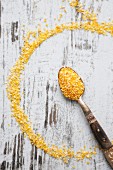 Couscous on a spoon and a wooden background (seen from above)