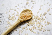 Long-grain rice on a wooden spoon on a wooden background