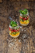 Rice salad in a glass jar with wild rice, sweetcorn, cucumber, tomato and lamb's lettuce