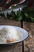 Parmesan in eine Schale mit Ricotta, Ei, Salz und Pfeffer reiben