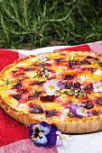 Summery beetroot quiche with feta and pansies on a picnic blanket