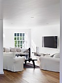 Flatscreen TV and black coffee table in white lounge area