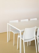 White table with glass top and designer chairs in front of empty wall