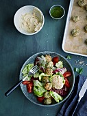 Hummus bowl with fish balls and brightly coloured salad