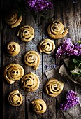 Cinnamon rolls on a wooden background, with violet lilac flowers