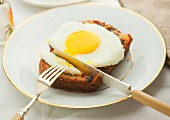 Poached egg on banana bread cut with a knife and fiork