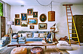 Holztisch mit Bücherstapel, Sofa und Bildergalerie im Vintage Wohnzimmer mit weiß gestrichener Ziegelwand