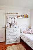 Shabby chest of drawers and blackboard with alphabet next to the bed in the nursery