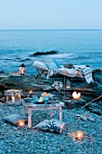 Romantisches Picknick mit Windlichtern, Laternen, Liege und Kissen am Meer
