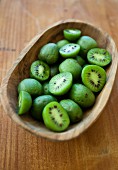Kiwi berries (mini kiwi) in a wooden bowl on a rustic wooden surface