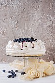 Homemade meringue cake Pavlova with whipped cream, fresh blueberries and blueberry sauce on vintage cake stand