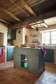 Island counter in Mediterranean kitchen with distressed blue and red cabinets