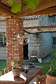 Spherical glass lamp above wooden table on roofed terrace