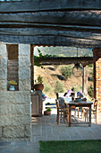 Wooden table on roofed terrace in Mediterranean garden