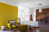 Yellow wall and artistic mixture of furnishings in open-plan interior