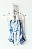 Sports bag hand-dyed with Shibori pattern hung from wire coathanger