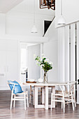 Round dining table with a bouquet and replicas of classic chairs in an open living area